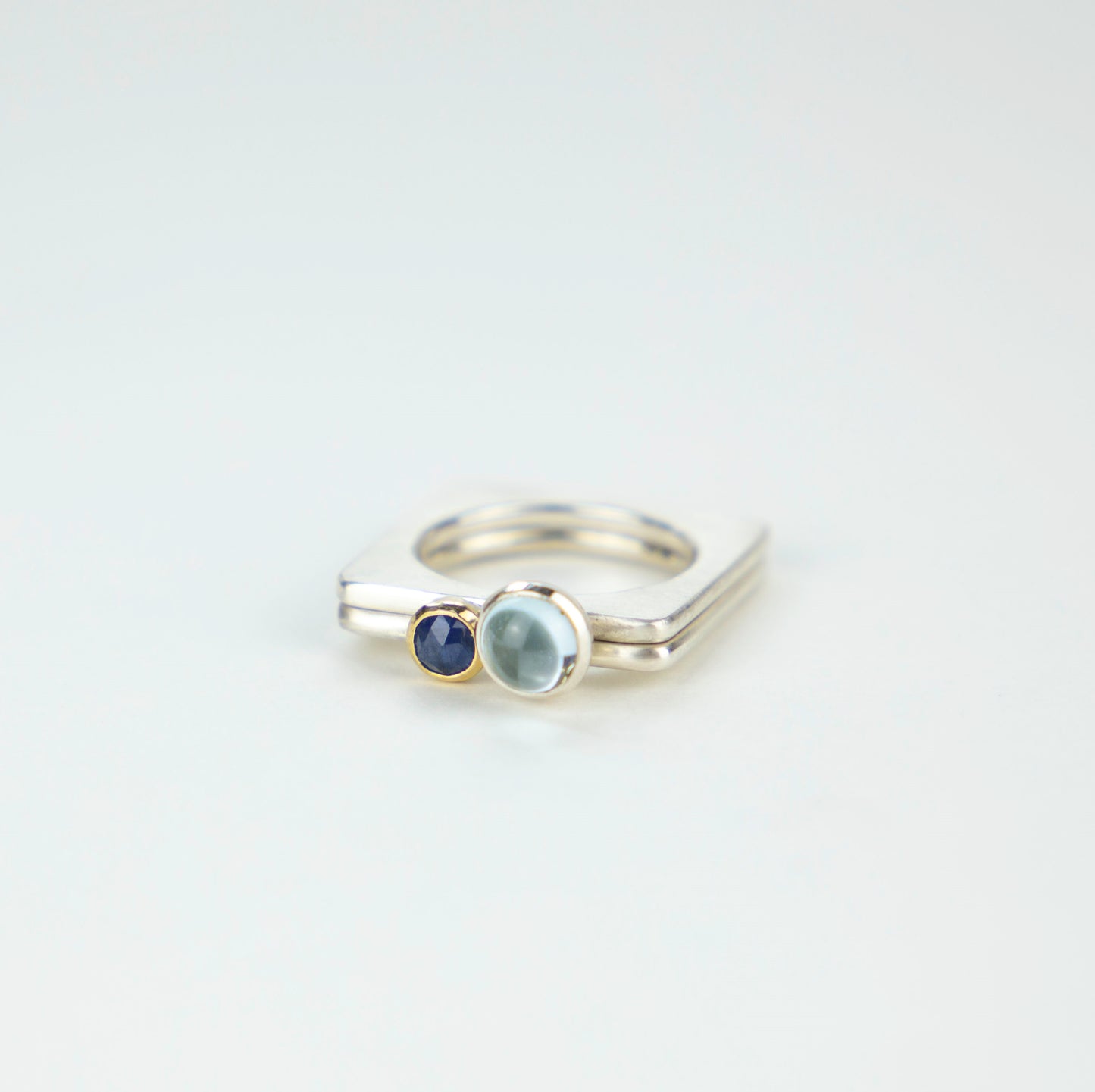 A square silver ring with a rich blue rosecut sapphire set in gold.