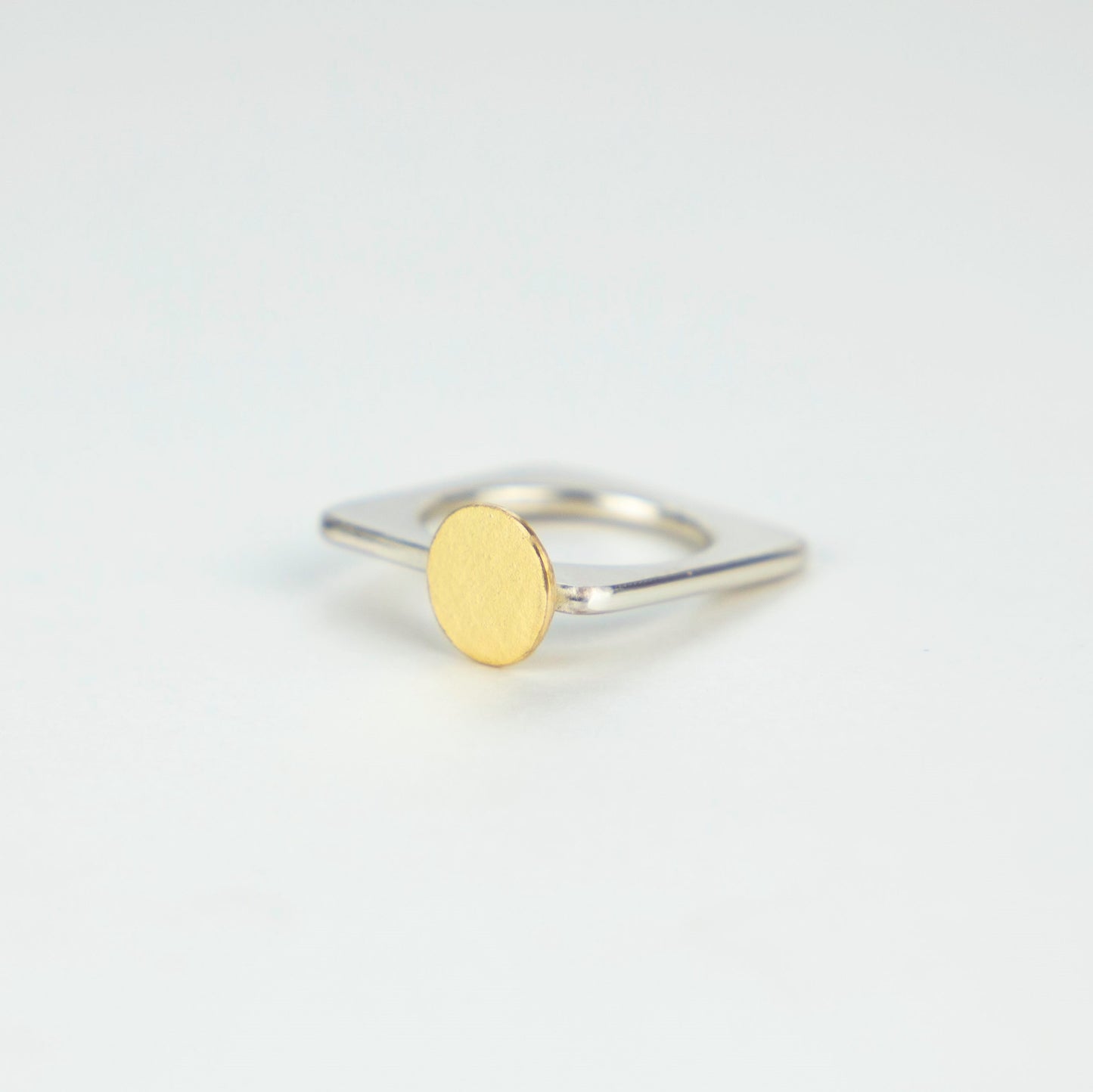 A square ring in silver with a gold disc or 'Moon'.