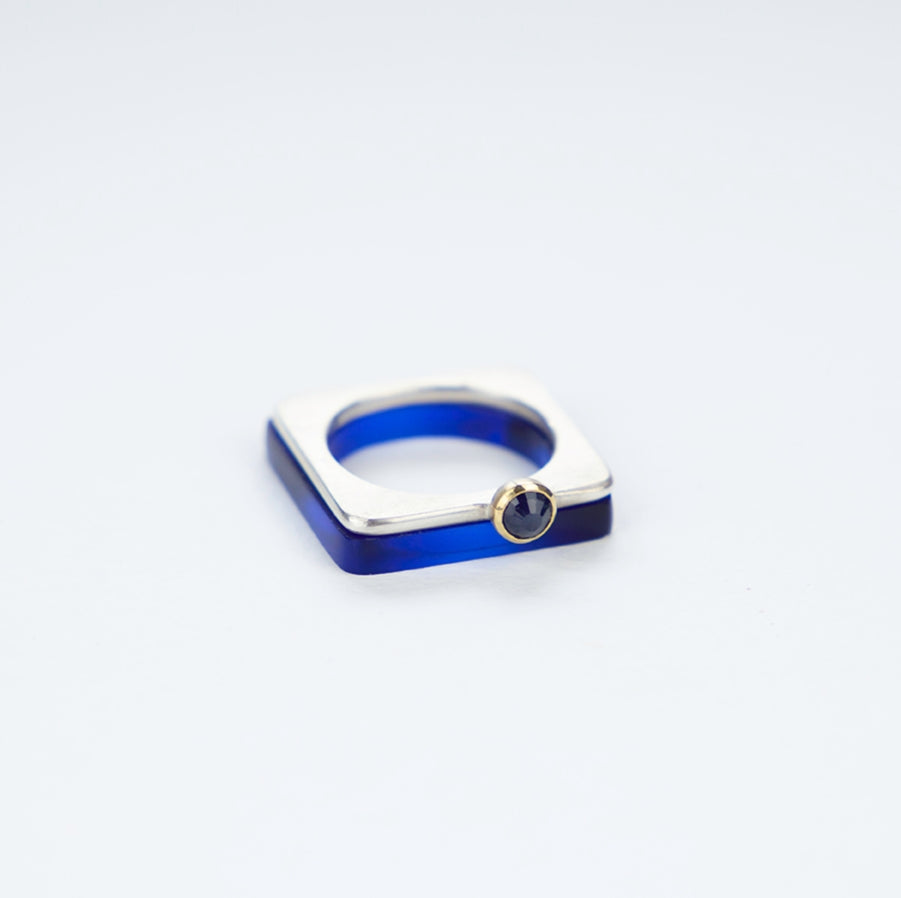 A square silver ring with a rich blue rosecut sapphire set in gold.