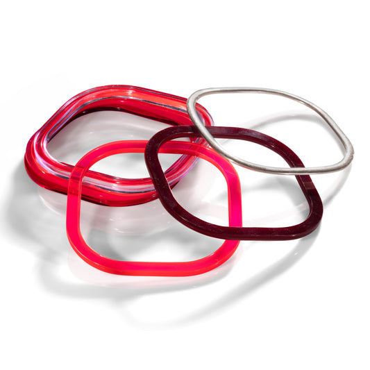 Stack of red acrylic and silver square bangles highlighting fluorescent pink and chocolate brown  and silver bangles. barbaraspence.co.uk
