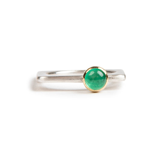 A square silver ring with a vivid green emerald set in gold.