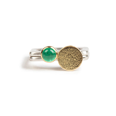 A square silver ring with a vivid green emerald set in gold.