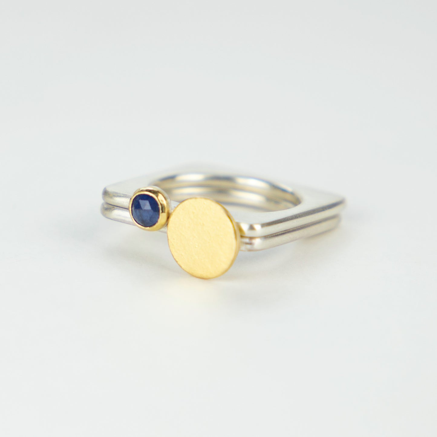 A square silver ring with a rich blue rosecut sapphire set in gold.