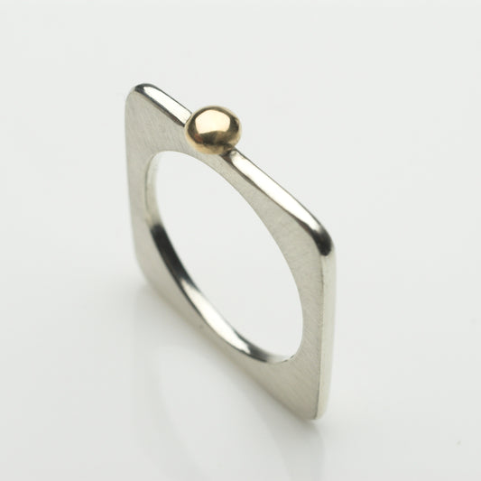 A square ring in silver with a gold ball.